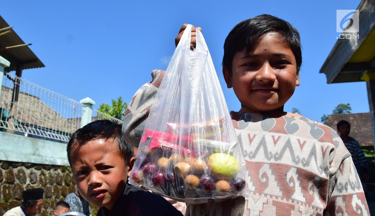 Seorang anak menunjukkan makanan di Kabupaten Boyolali, Kamis (3/5). Tradisi ini Sebagai perayaan menyambut datangnya bulan ramadan, kemudian dilanjutkan makan bersama di pertigaan jalan desa. (Liputan6.com/Gholib)
