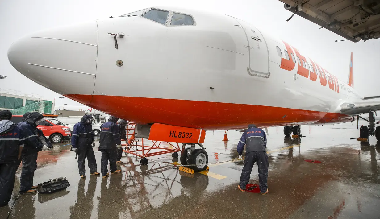 <p>Mekanik maskapai Jeju Air mengikat sebuah pesawat di landasan saat Topan Hinnamnor bergerak menuju Semenanjung Korea di Bandara Internasional Gimpo di Seoul, Korea Selatan, Senin (5/9/2022). Hembusan angin dan hujan lebat dari Topan Hinnamnor diperkirakan mencapai hingga 290 kilometer (180 mil) per jam. (Korea Pool/Yonhap via AP)</p>