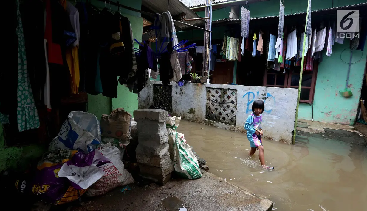 Seorang anak melintasi banjir di permukiman Jati Padang, Jakarta, Kamis (30/11). Banjir yang terjadi tersebut akibat tanggul darurat di Kali Pulo jebol karena genangan air yang cukup deras dan membanjiri permukiman sekitar. (Liputan6.com/Johan Tallo)