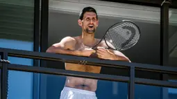 Petenis pria peringkat satu dunia, Novak Djokovic menyapa penggemarnya disela-sela menjalani latihan dari balkon hotel, Adelaide, Australia, Rabu (20/1/2021). (Foto: AFP/Morgan Sette)
