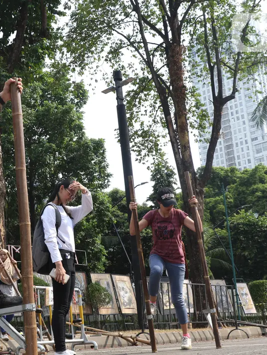 Pengunjung mencoba permainan tradisional Egrang pada Pekan Kebudayaan Nasional di Istora Senayan, Jakarta, Sabtu (12/10/2019). Perhelatan itu dimeriahkan kompetisi olahraga tradisional berupa permainan rakyat seperti egrang, lari balok, terompah panjang, dan hadang.. (Liputan6.com/Angga Yuniar)