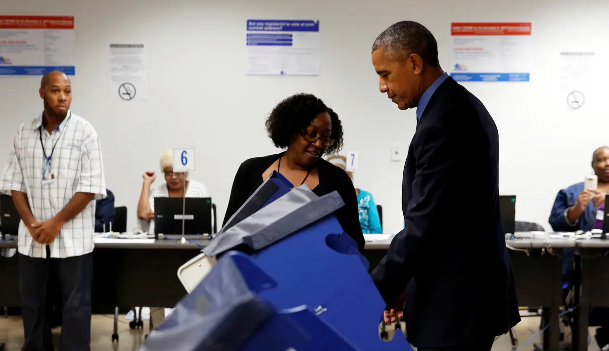 Pekerja membantu Presiden AS Barack Obama ketika akan memberikan suaranya di mesin voting elektronik di TPS awal di pusat kota Chicago, Jumat (7/10). Obama memberikan suaranya lebih awal untuk Pilpres AS pada 8 November 2016. (REUTERS/Jonathan Ernst)