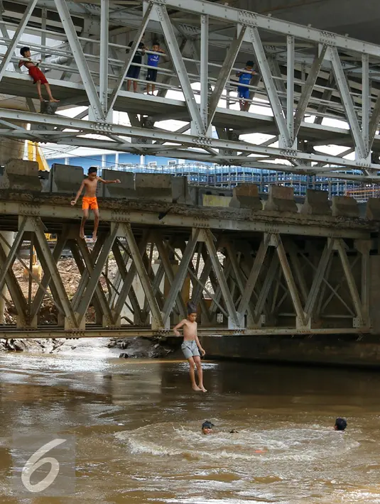 Anak-anak Ciliwung tampak riang saat melompat ke aliran sungai Ciliwung dari atas jembatan Kalibata, Jakarta, Jumat (13/11). Meningginya air sungai Ciliwung dimanfaatkan anak-anak Ciliwung untuk berenang dan bermain air. (Liputan6.com/Yoppy Renato)