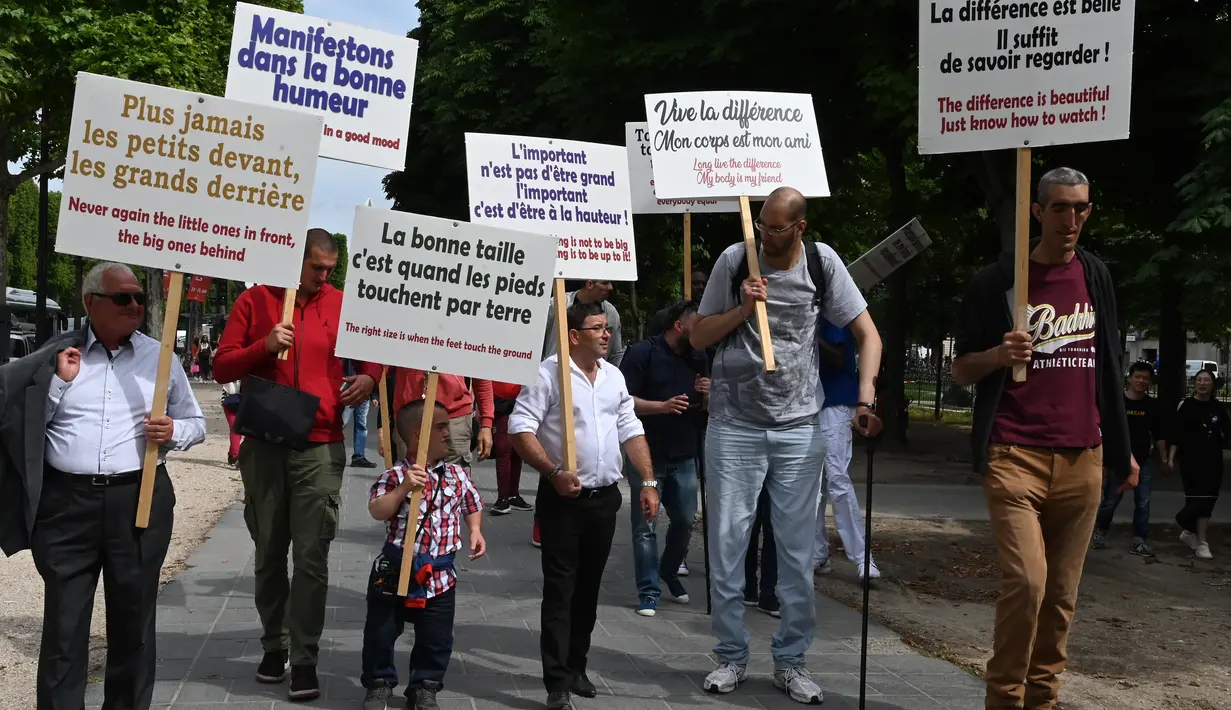 Sejumlah pria bertubuh tinggi berjalan sambil membawa poster saat melakukan pertemuan di Champs-Elysees Avenue di Paris, Prancis (14/6/2019). Kemunculan mereka di Champs-Elysees Avenue sampai mengundang perhatian warga dan penyiar televisi. (AFP Photo/Dominique Faget)
