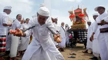 Seorang pria menusukkan keris ke tubuhnya saat menggelar ritual Melasti di Bali, Senin (4/3). Ritual Melasti ini dirayakan menjelang Nyepi 2019. (AP Photo/Firdia Lisnawati)