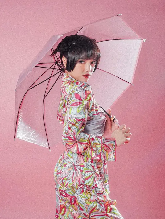 Penampilan yang super playful dari Fuji. Ia mengenakan busana bersiluet kimono bernuansa merah muda dengan detail semacam obi abu-abu yang melilit perutnya. Rambut ditata dengan gaya edgy dan Fuji juga membawa properti payung yang membuat penampilannya semakin manis. [Foto: Instagram/fuji_an]