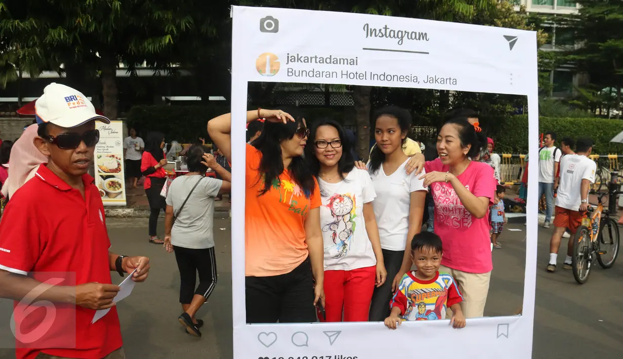 Warga berpose di salah satu booth Instagram di Bundaran HI, Jakarta, Minggu (16/4). Ratusan tanda tangan tersebut di bentuk untuk mendukung pilkada DKI Jakarta yang damai dan tidak golput. (Liputan6.com/Angga Yuniar)