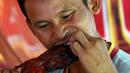 Seorang pria memakan tikus bakar di sebuah kios di provinsi Battambang, Kamboja (8/8/2019). Tikus bakar yang tusuk sate harganya masing-masing 0,25 USD atau sekitar 3500 rupiah. (AFP Photo/Tang Chhin Sotthy)