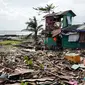 Warga berjalan melewati sebuah rumah yang rusak akibat terjangan topan Phanfone di Tacloban, Provinsi Leyte, Filipina, Rabu (25/12/2019). Topan membuat jutaan warga di negara yang mayoritas beragama Katolik itu merayakan Natal dengan kesedihan. (Bobbie ALOTA/AFP)