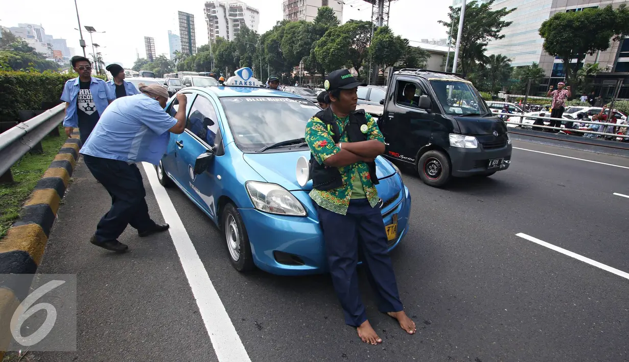Seorang sopir menghalangi taksi saat demo di depan Gedung DPR/MPR, Jakarta, Selasa (22/3). Selain melakukan demo, sopir taksi tersebut melakukan sweeping ke supir taksi yang beroperasi di dalam tol dan membakar ban. (Liputan6.com/Immanuel Antonius)