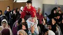 Sebagai informasi, hingga Maret 2026, eskalasi serangan udara Israel di Beirut, Lebanon, semakin intensif. Tampak dalam foto, para pria mengangkat dua anak kecil selama acara di mana para sukarelawan menyiapkan bingkisan makanan dan manisan Idulfitri untuk keluarga pengungsi yang merayakan hari raya jauh dari rumah mereka, di sebuah universitas negeri yang diubah menjadi tempat penampungan setelah serangan udara Israel di Beirut, Lebanon, Jumat, 20 Maret 2026. (AP Photo/Hassan Ammar)