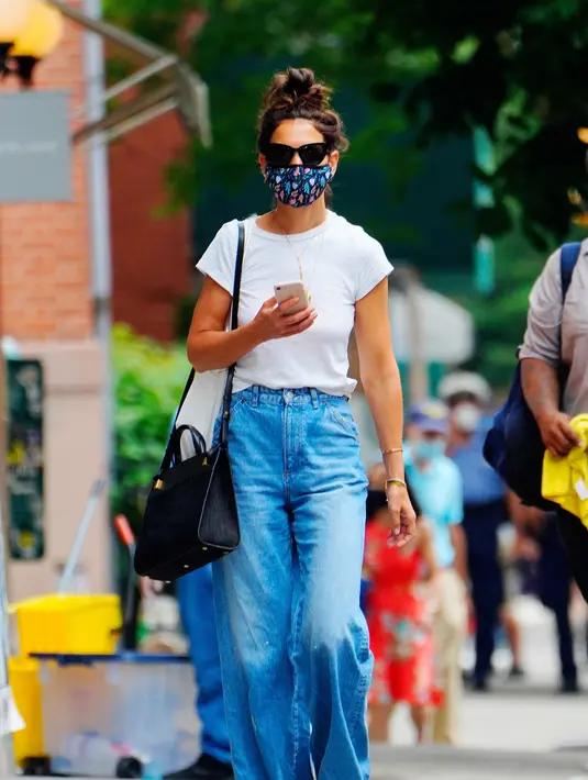Katie Holmes tampil kasual untuk musim panas dengan celana jeans wide legs, sepatu kets, dan tas Métier London Perriand. Foto: Vogue.