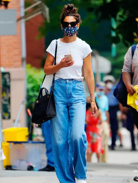 Katie Holmes tampil kasual untuk musim panas dengan celana jeans wide legs, sepatu kets, dan tas Métier London Perriand. Foto: Vogue.