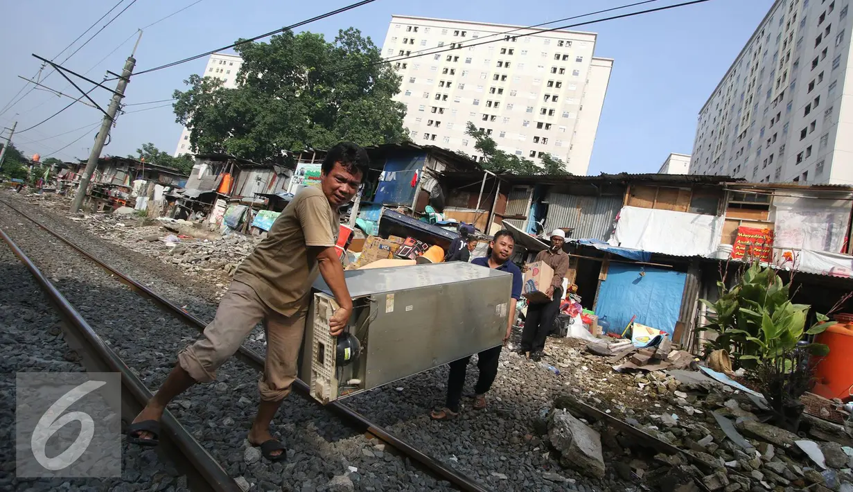 Warga membawa barang berharga saat alat berat merobohkan bangunan di kawasam Rawajati, Jakarta, Kamis (1/9). Penertiban tersebut menyebabkan warga terpaksa menyelamatkan barang berharga mereka ke tepi rel kereta api. (Liputan6.com/Immanuel Antonius)