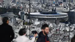 Orang-orang melihat Stadion Nasional Tokyo untuk Olimpiade dan Paralimpiade Tokyo 2020 setelah selesai direnovasi di Tokyo (30/11/2019). Stadion lima lantai itu akan menampung 60.000 penggemar. (AFP Photo/Charly Triballeau)