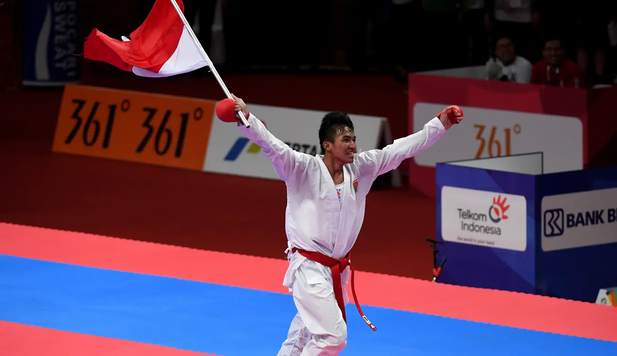 Karateka Indonesia, Rifki Ardiansyah Arrosyiid mengibarkan bendera Merah Putih setelah mengalahkan Amir Mahdi Zadeh asal Iran dalam final karate putra 60kg Asian Games 2018 di Jakarta, Sabtu (25/8). (ANTARA FOTO/INASGOC/Yudhi Ginanjar/Sup/18)