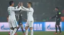 Pemain Real Madrid, Cristiano Ronaldo dan Raphael Varane, merayakan kemenangan atas PSG pada laga Liga Champions di Stadion Parc des Princes, Paris, Selasa (6/3/2018). Madrid berhasil lolos ke delapan besar. (AFP/Christophe Simon)