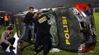 Petugas memeriksa kendaraan polisi yang rusak menyusul kerusuhan pada pertandingan sepak bola antara Arema Vs Persebaya di Stadion Kanjuruhan, Malang, Jawa Timur, 1 Oktober 2022. Selain korban meninggal dunia, tercatat ada 13 unit kendaraan yang mengalami kerusakan, 10 di antaranya merupakan kendaraan Polri. (AP Photo/Yudha Prabowo)