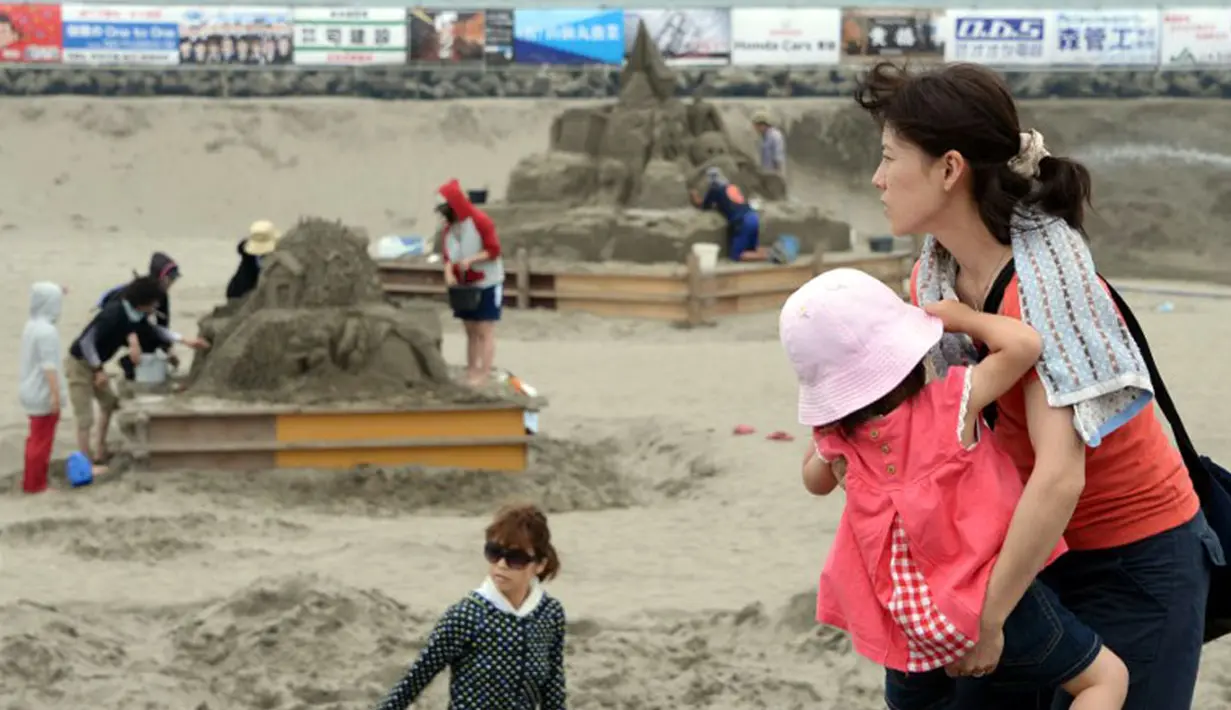 Warga mengunjungi pameran Asahi Sand Sculpture di pantai Yasashigaura, Asahi, Chiba, (13/7/2014). Diharapkan, pameran patung pasir ini mampu menarik minat sekitar 50.000 wisatawan. (AFP PHOTO/Toshifumi Kitamura)