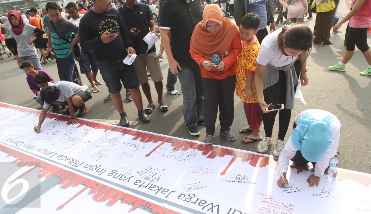 Sejumlah warga melakukan tanda tangan di bentangan sapanduk panjang di Bundaran HI, Jakarta, Minggu (16/4). Ratusan tanda tangan tersebut di bentuk untuk mendukung pilkada DKI Jakarta yang damai dan tidak golput. (Liputan6.com/Angga Yuniar)