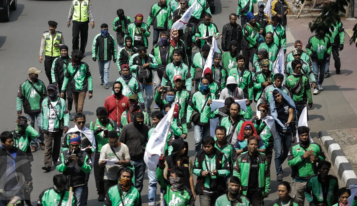 Massa dari pengemudi ojek online membentangkan spanduk sambil bergerak menuju Istana Negara, Jakarta, Senin (15/5). Mereka menuntut agar pemerintah segera merevisi UU No 22 Tahun 2009 tentang Lalu Lintas dan Angkutan Jalan. (Liputan6.com/Faizal Fanani)