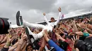 Pembalap Mercedes Lewis Hamilton melakukan selebrasi bersama penggemarnya usai berhasil memenangkan GP Inggris di sirkuit Silverstone, (16/7).  Hamilton berhasil menjuarai GP Inggris untuk kali keempat secara beruntun. (AFP Photo/Andrej Isakovic)