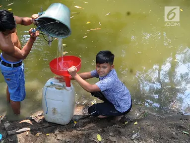 Dua anak Kampung Gamblok mengambil sisa air Kali Cihoe, Desa Ridomanah, Bekasi, Jawa Barat, Kamis (15/8/2019). Kemarau panjang sejak awal Ramadan memaksa warga mencari sisa air untuk diminum.