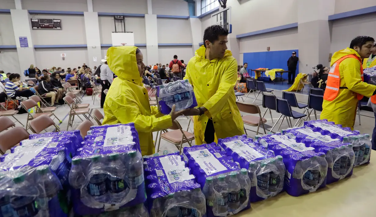 Sejumlah petugas menyiapkan air mineral untuk warga yang sedang menunggu proses evakuasi di Corpus Christi, Texas, Jumat (25/8). Badai Harvey yang diperkirakan paling kuat sepanjang 12 tahun bakal menghantam daratan Amerika Serikat. (AP Photo/Eric Gay)