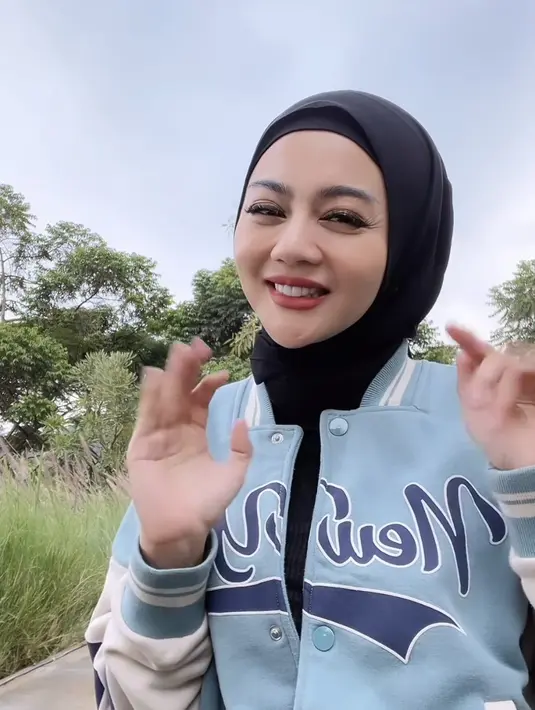 Ia juga mengenakan jaket varsity biru dipadukan kerudung hitamnya.  (@jenitajanet)