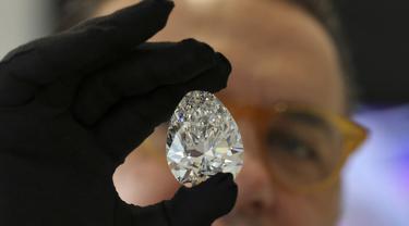 Seorang petugas rumah lelang Christie memperlihatkan sebuah berlian raksasa yang dijuluki "The Rock" kepada media di Dubai, Jumat (25/3/202). Berlian tersebut dipamerkan menjelang pelelangan yang diperkirakan akan terjual hingga USD30 juta atau sekitar Rp430 miliar. (Karim SAHIB/AFP)