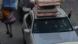 Warga berbondong-bondong meninggalkan rumah mereka menggunakan kendaraan yang dipenuhi barang berharga, kemacetan panjang di sejumlah jalur utama tak terhindarkan. Tampak dalam foto, sebuah keluarga mengacungkan tanda kemenangan saat mereka melarikan diri dari serangan udara Israel di Dahiyeh, pinggiran selatan Beirut, Lebanon, Kamis 5 Maret 2026. (AP Photo/Bilal Hussein)