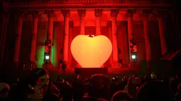 Masyarakat mengagumi instalasi seni bercahaya bertajuk 'With Love ...'  karya seniman Prancis Franck Pelletier  yang diproyeksikan di Balai Kota Leeds, utara Inggris, 10 Oktober 2019. Festival tersebut menampilkan proyeksi, instalasi interaktif, eksebisi, dansa, dan musik. (Oli SCARFF/AFP)