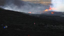 Orang-orang melihat aktivitas di gunung berapi Fagradalsfjall di Islandia pada Rabu (3/8/2022), yang terletak 32 kilometer (20 mil) barat daya ibu kota Reykjavik dan dekat dengan Bandara Internasional Keflavik. Para ilmuwan telah mengantisipasi letusan dari suatu tempat di Semenanjung setelah serangkaian gempa bumi terjadi selama seminggu terakhir. (AP Photo/Brynjar Gunnarsson)