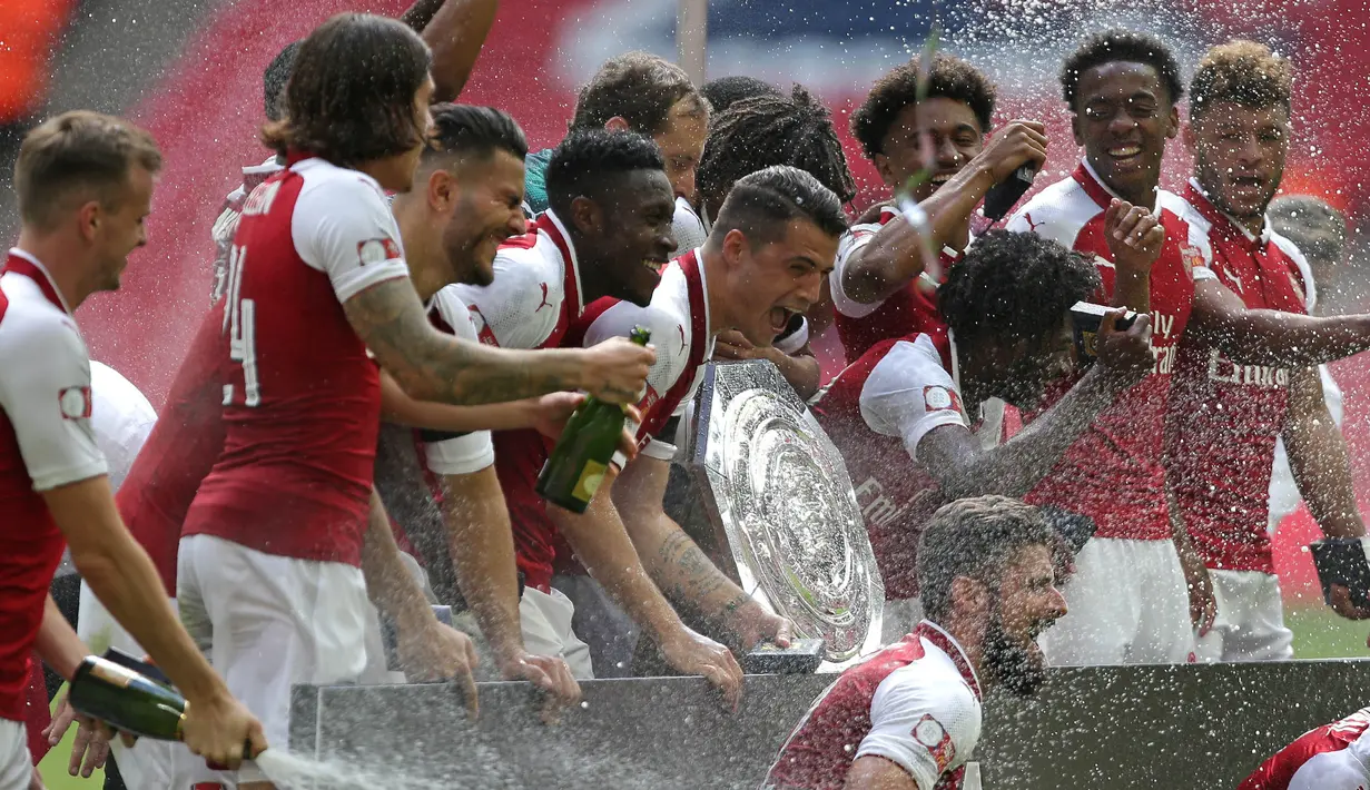 Para pemain Arsenal menyemprot sampanye saat merayakan gelar Community Shield usai mengalahkan Chelsea di Stadion Wembley, London, Minggu (6/8/2017). Ini merupakan trofi Community Shield yang ke-15 bagi Arsenal. (AFP/Ian Kington)