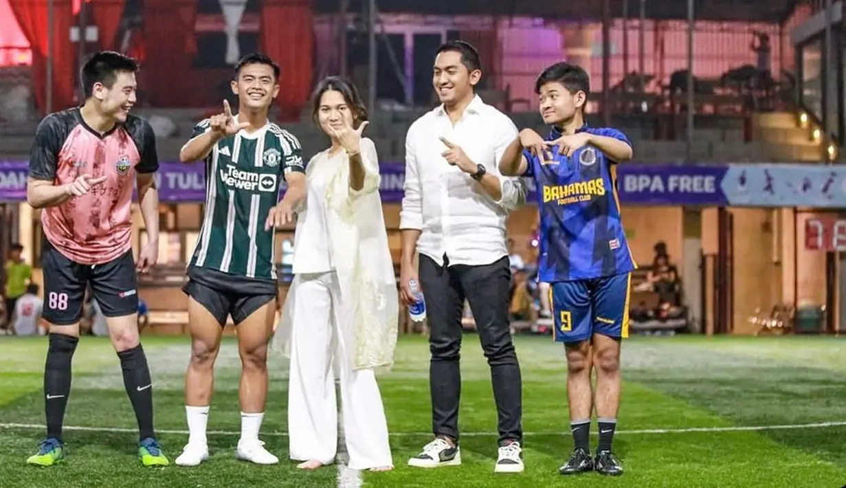 Bahkan ada momen di mana Azizah Salsha masih memakai baju kondangannya turun ke lapangan bola, berpose bersama sang suami yang telah mengenakan jerseynya. [Foto: Instagram/arhanzize__]