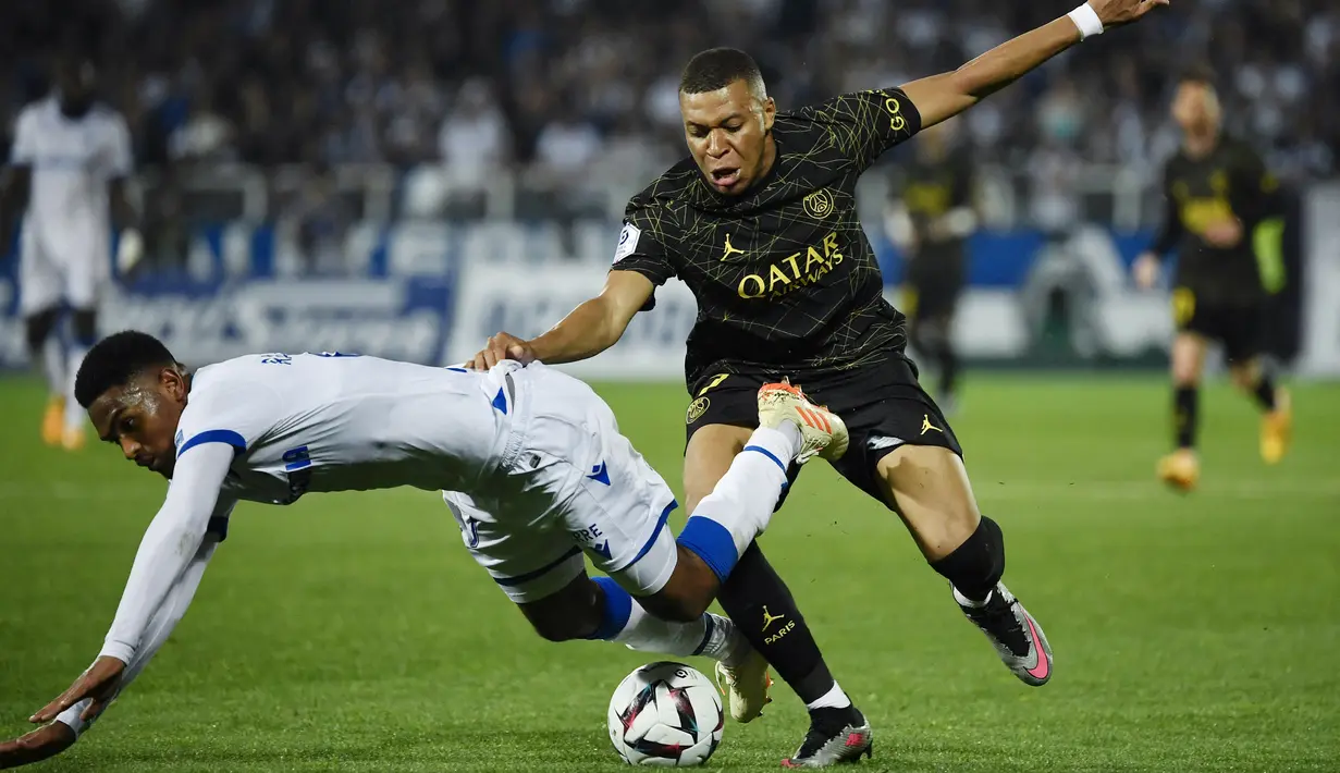 Pemain Paris Saint-Germain (PSG), Kylian Mbappe, berebut bola dengan pemain AJ Auxerre, Rayan Raveloson, pada laga Liga Prancis, di Stade de I’Abbe Deschamps, Senin (22/5/2023). PSG menang dengan skor tipis 2-1. (AFP/Julien De Rosa)