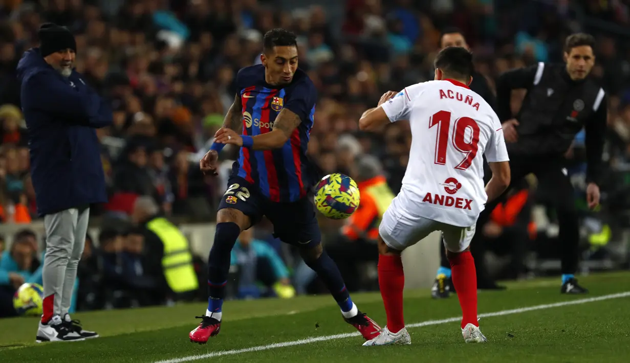 Penyerang Barcelona Raphinha berebut bola dengan bek Sevilla Marcos Acuna pada jornada ke-20 La Liga 2022/2023 di Camp Nou, Senin (6/2/2023) dini hari. Kemenangan atas Sevilla menandai Barcelona tidak terkalahkan dalam 11 pertandingan berturut-turut di LaLiga. (AP Photo/Joan Monfort)
