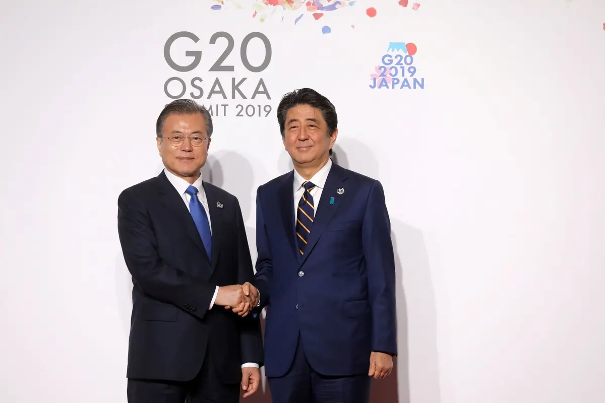 Presiden Korea Selatan (kiri) berjabat tangan dengan Perdana Menteri Jepang Shinzo Abe (kanan) di KTT G-20 tahun 2019 (AFP/Ludovic Marin)