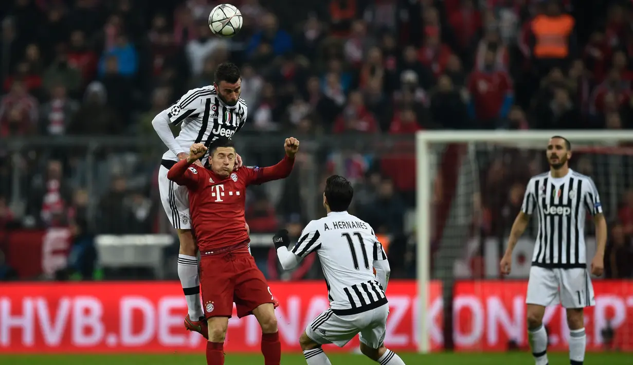 Penyerang Muenchen, Robert Lewandowski (tengah) berebut bola udara dengan bek Juventus, Andrea Barzagli pada leg kedua 16 besar liga champions di Stadion Allianz Arena, Kamis (17/3). Muenchen menang atas Juventus dengan skor 4-2. (AFP/ODD ANDERSEN)