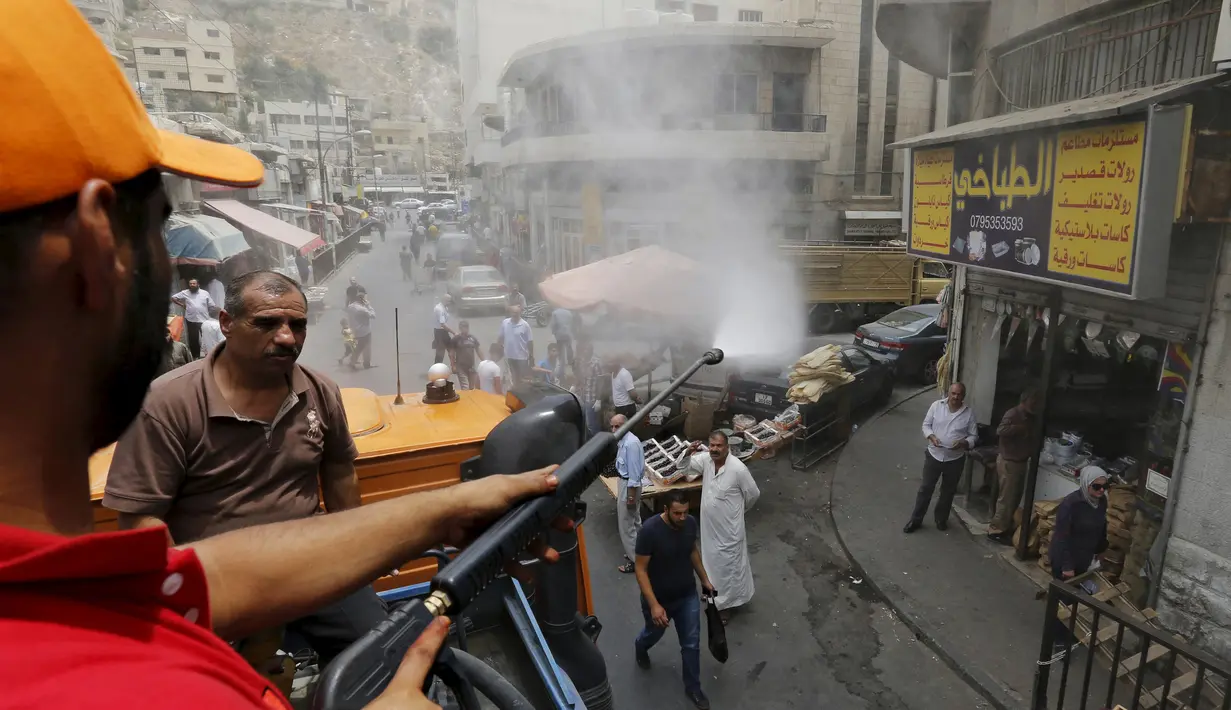 Personel dinas Kota Amman menyemprot warga dengan sprinkler air untuk mengurangi efek dari gelombang panas di Yordania, Senin(3/8/2015). (REUTERS/Muhammad Hamed)