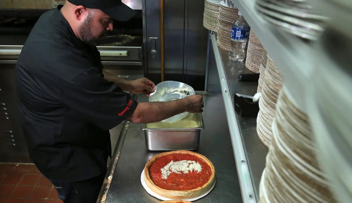 Chief Cook, Fabian Martinez menyelesaikan pembuatan pizza bergambar wajah calon presiden AS dari Partai Republik, Donald Trump dan rivalnya dari Partai Demokrat, Hillary Clinton di Giordano Pizzeria, Chicago, Selasa (27/9). (REUTERS / Jim Young)