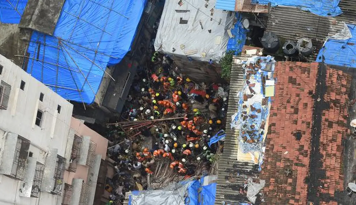 Petugas pemadam kebakaran India mencari korban setelah sebuah bangunan ambruk di Mumbai (16/7/2019). Dua orang tewas dan sedikitnya 40 terperangkap di bawah puing-puing setelah bangunan ambruk ketika hujan lebat. (AFP Photo/Punit Paranjpe)