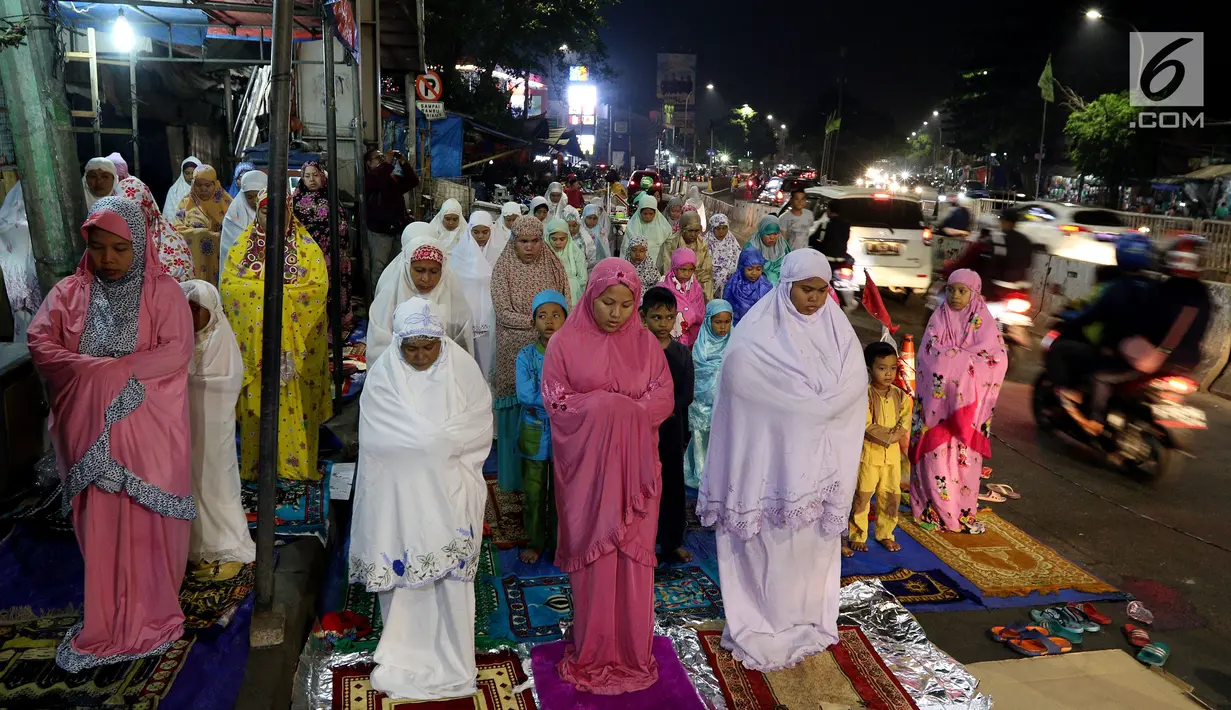 Jemaah wanita melaksanakan salat tarawih hingga ke badan jalan akibat melubernya Musala Miftahul Jannah di Kawasan Pasar Gembrong, Jakarta, Kamis (17/5). (Liputan6.com/JohanTallo)