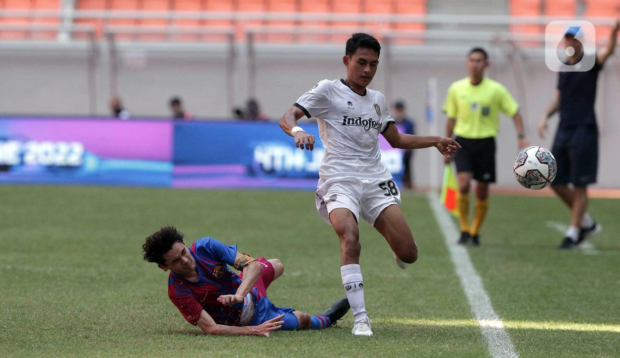 Pemain Bali United U-18 Anak Agung Dwi Trisna Putra (kanan) berebut bola dengan pemain pemain Barcelona U-18 Joan Anaya Balaña pada pertandingan International Youth Championship (IYC) 2021 di Jakarta International Stadium (JIS), Jakarta, Minggu (17/4/2022). (Liputan6.com/Faizal Fanani)