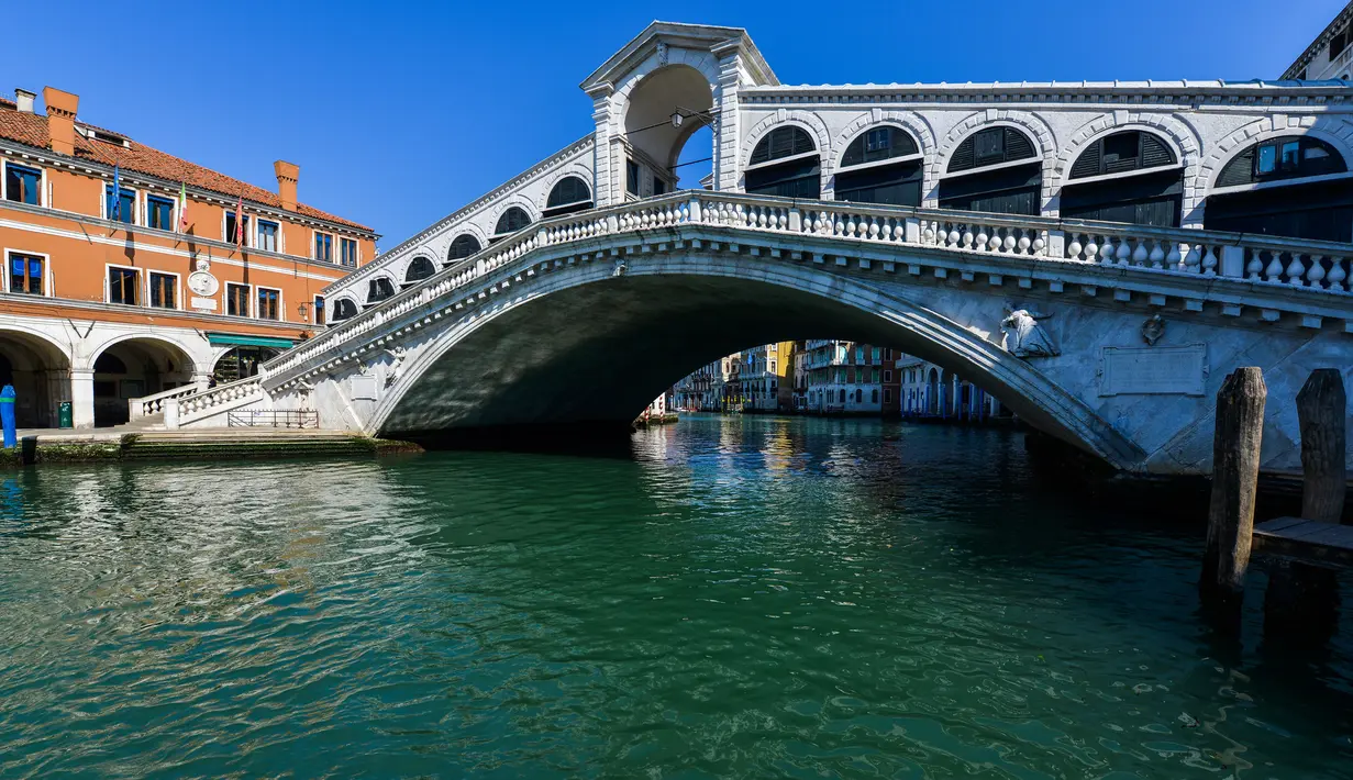Pandangan umum menunjukkan perairan yang lebih jernih Grand Canal di Jembatan Rialto di Venesia pada 18 Maret 2020. Sejak Italia memberlakukan lockdown akibat pandemi virus corona, air di Kanal Venesia yang biasanya keruh dan gelap berubah menjadi jernih. (ANDREA PATTARO / AFP)