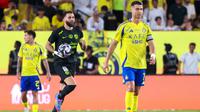 Pemain depan Nassr asal Portugal #7, Cristiano Ronaldo, bereaksi saat pemain depan Ittihad asal Prancis #09 Karim Benzema merayakan gol pertama timnya selama pertandingan sepak bola Liga Pro Saudi antara Al-Nassr dan Al-Ittihad di Taman Al-Awwal di Riyadh, Kamis dini hari WIB (8-5-2025). (Fayez NURELDINE/AFP)