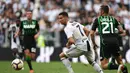Striker Juventus, Cristiano Ronaldo, menghindari kejaran pemain Sassuolo pada laga Serie A di Stadion Juventus, Turin, Minggu (16/9/2018). CR 7 cetak dua gol, Juve menang 2-0 atas Sassuolo. (AFP/Miguel Medina)
