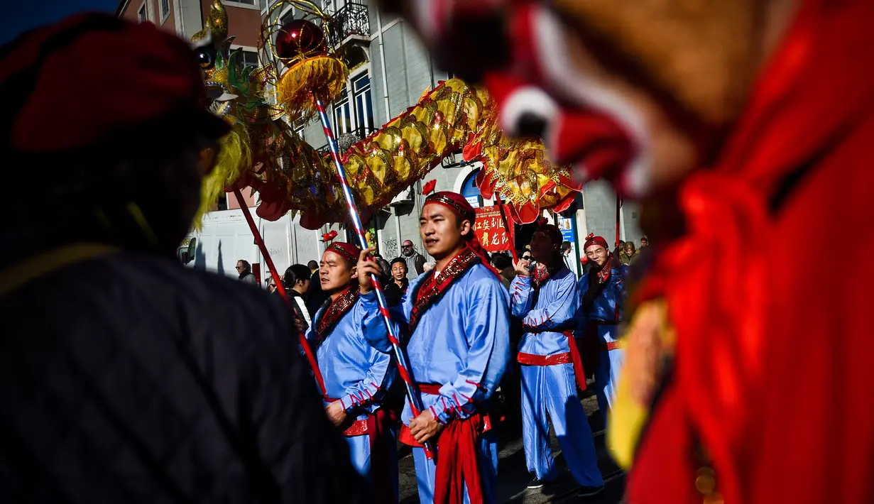 Sejumlah orang membawakan tarian Naga saat perayaan menjelang tahun baru China di Lisbon, Portugal (21/1). Menjelang Imlek, warga keturunan Tionghoa di Portugal juga merayakannya dengan karnaval di sekitar jalan Kota Lisbon. (AFP/Patricia De Melo Moreira)