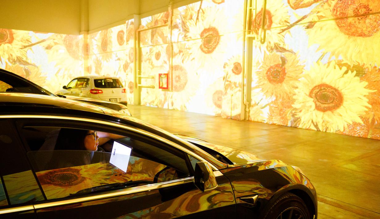 Orang-orang duduk di mobil mereka menikmati pameran seni Vincent Van Gogh di Toronto, Ontario, Kanada pada 3 Juli 2020. Pameran seni di masa pandemi Covid-19 mendatangkan ide kreatif para penyelenggara kegiatan dengan memamerkan hasil karya seni lewat konsep drive-in. (Cole BURSTON/AFP)