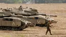 Tentara Israel berjalan melewati tank di dekat perbatasan Gaza-Israel, Jumat (19/10). Pengerahan itu disebut menjadi yang terbesar sejak perang 2014. (JACK GUEZ/AFP)